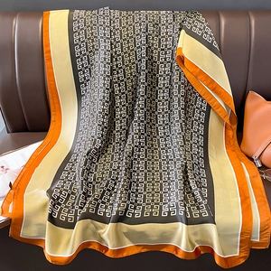 Detail of silk-touch shawl with orange and black geometric patterns on a leather sofa