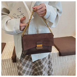 Gros plan du sac bandoulière en daim marron avec chaîne dorée et fermoir métallique