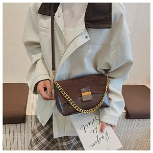 Détail du sac à bandoulière en daim avec chaîne dorée porté par un mannequin femme