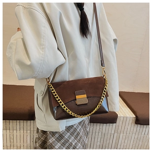 Détail du sac bandoulière marron foncé avec patchwork en daim et chaîne dorée