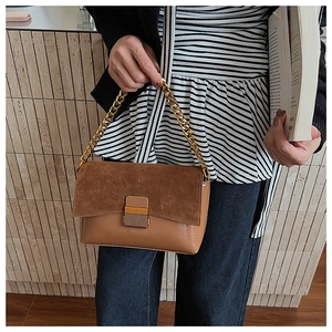 Détail du sac à bandoulière en daim marron avec chaîne dorée et boucle métallique chic