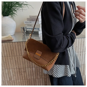 Détail du sac bandoulière en daim rétro montrant les coutures et la boucle en métal