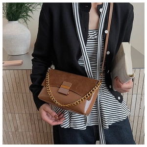 Détail du sac bandoulière en patchwork daim et cuir avec chaîne dorée et fermoir métal