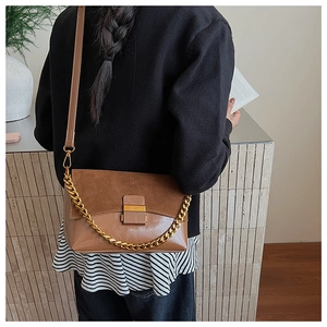 Détail du sac bandoulière rétro en daim avec boucle métallique porté par un mannequin