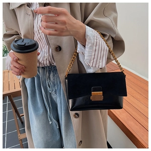 Sac bandoulière rétro en cuir noir avec chaîne et fermoir doré porté par un mannequin