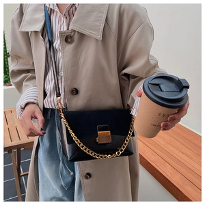 Détail du sac bandoulière vintage en daim avec chaîne dorée sur un trench-coat beige
