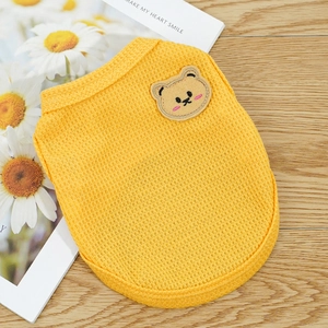 Macro detail of yellow waffle knit pet vest with cute bear embroidery on wood surface