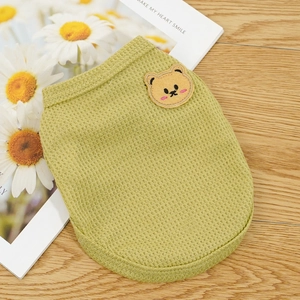 Detail of light green waffle knit pet vest featuring a cute bear patch on a wooden desk