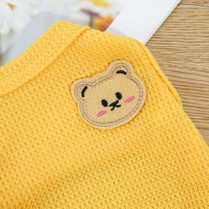 Close-up of yellow waffle knit pet vest featuring a cute bear embroidery patch