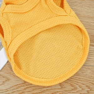 Macro shot of breathable waffle knit texture and stitching on yellow pet vest