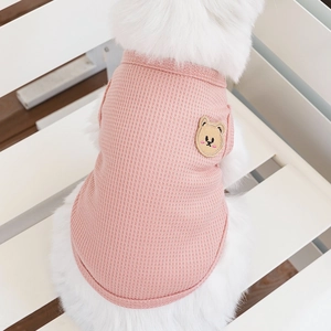 Detailed close-up of pink waffle knit pet vest with a cute bear patch on a fluffy dog