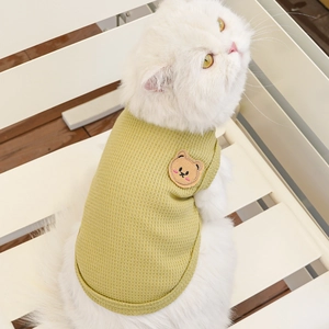 Detail of green waffle knit pet vest featuring a cute brown bear embroidery patch