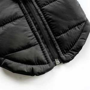 Close-up of a silver metal zipper on a black quilted winter vest for dogs