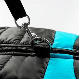 Detail of silver metal swivel hook and blue quilted fabric on a padded shoulder bag