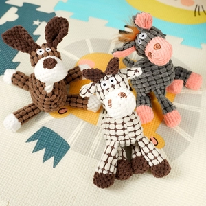 Three plush dog chew toys in puppy, donkey and giraffe shapes on a colorful play mat