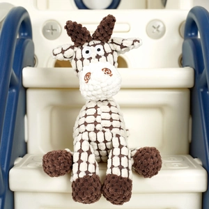 Close-up of a brown checkered crochet giraffe plush toy on a blue children's slide