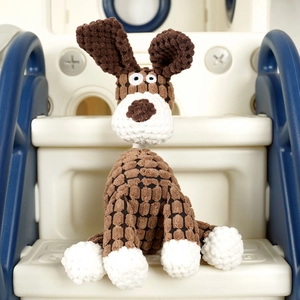 Detailed view of a brown checkered crochet dog plush toy sitting on a white platform