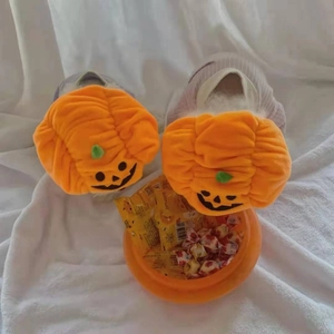 Makroaufnahme von flauschigen orangefarbenen Kürbis-Hausschuhen für Haustiere zu Halloween