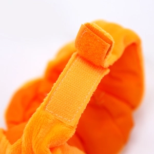 Makroaufnahme von orangefarbenem Plüsch-Haustierhut mit verstellbarem Klettverschluss