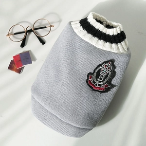 Macro detail of V-neck pet knit vest with embroidered crest and ribbed collar texture