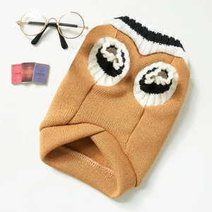 Detail of caramel knit pet sweater featuring cartoon eyes and striped V-neck collar