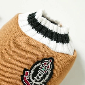 Detail of camel knit dog vest featuring an embroidered crown crest and V-neck ribbing