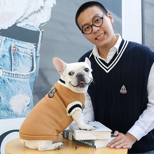 Detail of camel knit dog sweater with crest and matching owner's preppy navy vest