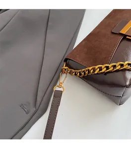 Détail du sac à main rétro en daim marron avec chaîne dorée brossée et finitions soignées