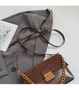 Gros plan du sac à bandoulière vintage marron avec chaîne dorée et rabat en daim