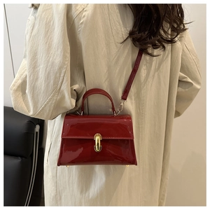 Dettaglio borsa in pelle verniciata rossa con fibbia dorata su un trench beige chic
