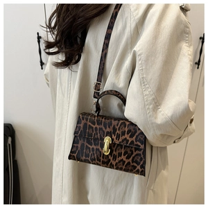 Detail of leopard print crossbody bag with gold twist lock and adjustable strap