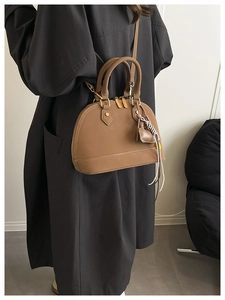 Dettaglio della borsa vintage marrone con finiture dorate e nappa sulla modella