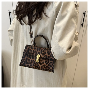 Leopard print crossbody bag with gold buckle lock worn over a white stylish coat