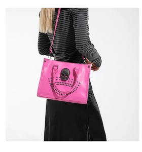 Detailed view of magenta tote bag with skull relief and stud accents on a model