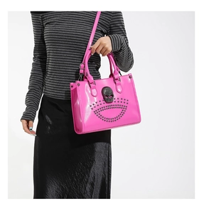 Close-up of pink patent tote bag with large crystal skull and metal rivet accents