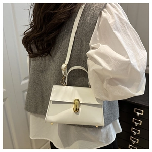 Detail of white glossy leather handbag showing golden metal lock and structured handle
