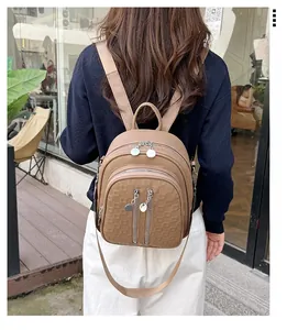 Close-up of khaki PU leather backpack with geometric texture and silver zippers on model
