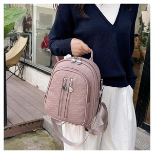 Detail of pink faux leather backpack with embossed grid texture and silver metal zippers