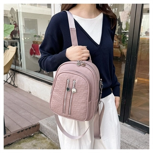 Detail of mauve PU leather backpack featuring geometric embossed patterns and zippers