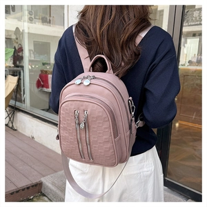 Detail of dusty pink leather backpack with embossed grid texture and silver zippers