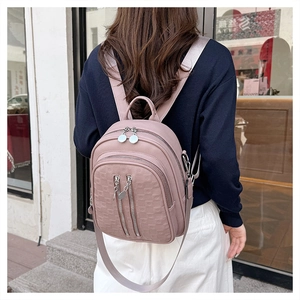Detailed back view of a pinkish purple textured leather backpack with zipper pockets