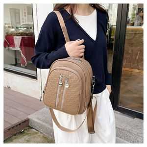 Detail of khaki soft leather crossbody bag with square embossed pattern and silver zippers