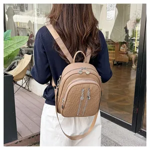 Detail of tan faux leather backpack featuring square embossing and silver zipper pockets