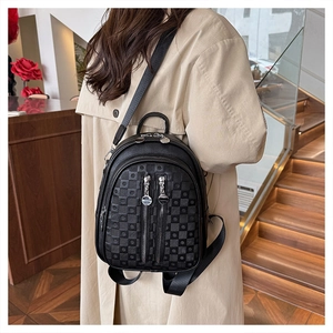 Detail of embossed black faux leather backpack showing checkered texture and silver zippers