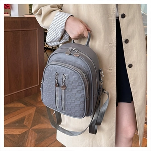 Close-up of gray PU leather backpack showing lychee texture and checkered embossed pocket