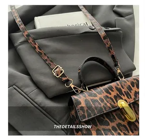 Gros plan du sac bandoulière léopard avec boucle dorée sur un blazer gris chic