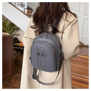 Detail of grey mini backpack with geometric embossing and metal zippers on a model