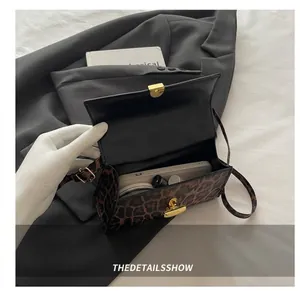 Vue intérieure du petit sac bandoulière léopard contenant téléphone et rouge à lèvres