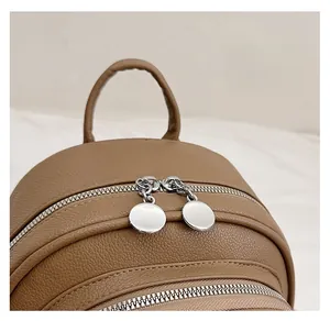 Detail of soft leather brown backpack featuring smooth dual metal zippers and a top handle