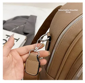 Detail view of brown pebbled leather bag featuring silver metal hook and detachable strap